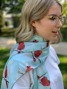 Long, rectangular light-weight scarf with light blue background and bright red northern cardinals.